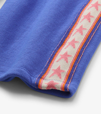 Close-up of blue track pants with pink star side stripe and orange trim
