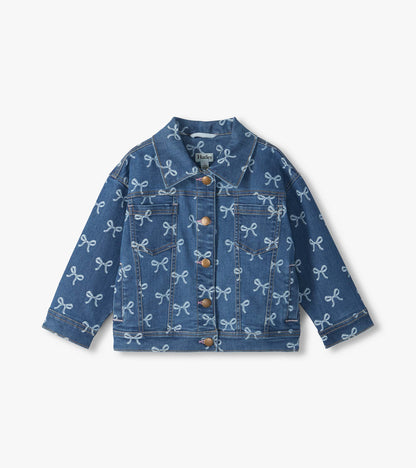 Front view of blue slouchy denim jacket with white bow print, chest pockets and brass-tone buttons