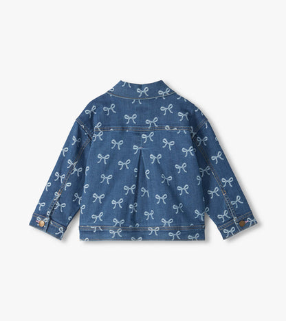 Back view of blue slouchy denim jacket with allover bow print, pleated back and button cuffs