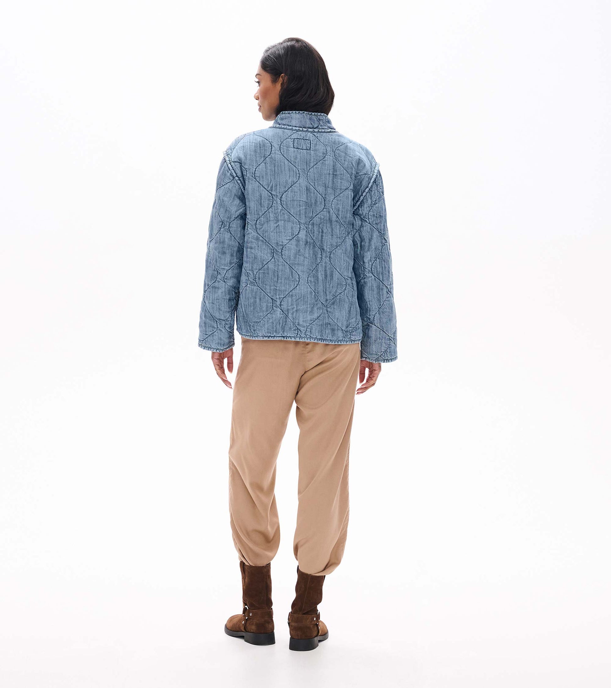Back view of blue acid rinse quilted jacket with curved quilted pattern and stand collar