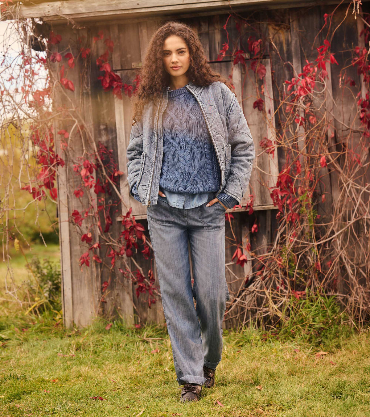Stellar blue cable knit sweater layered under a quilted jacket outdoors