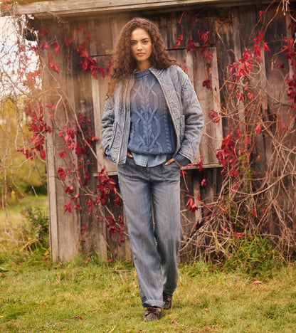 Stellar blue cable knit sweater layered under a quilted jacket outdoors
