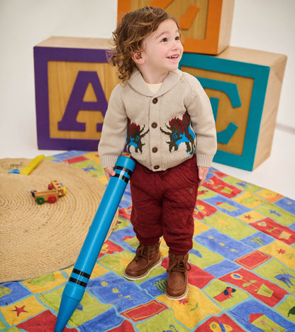 Toddler wearing an oatmeal shawl collar cardigan with colorful dinosaur knit design on the front
