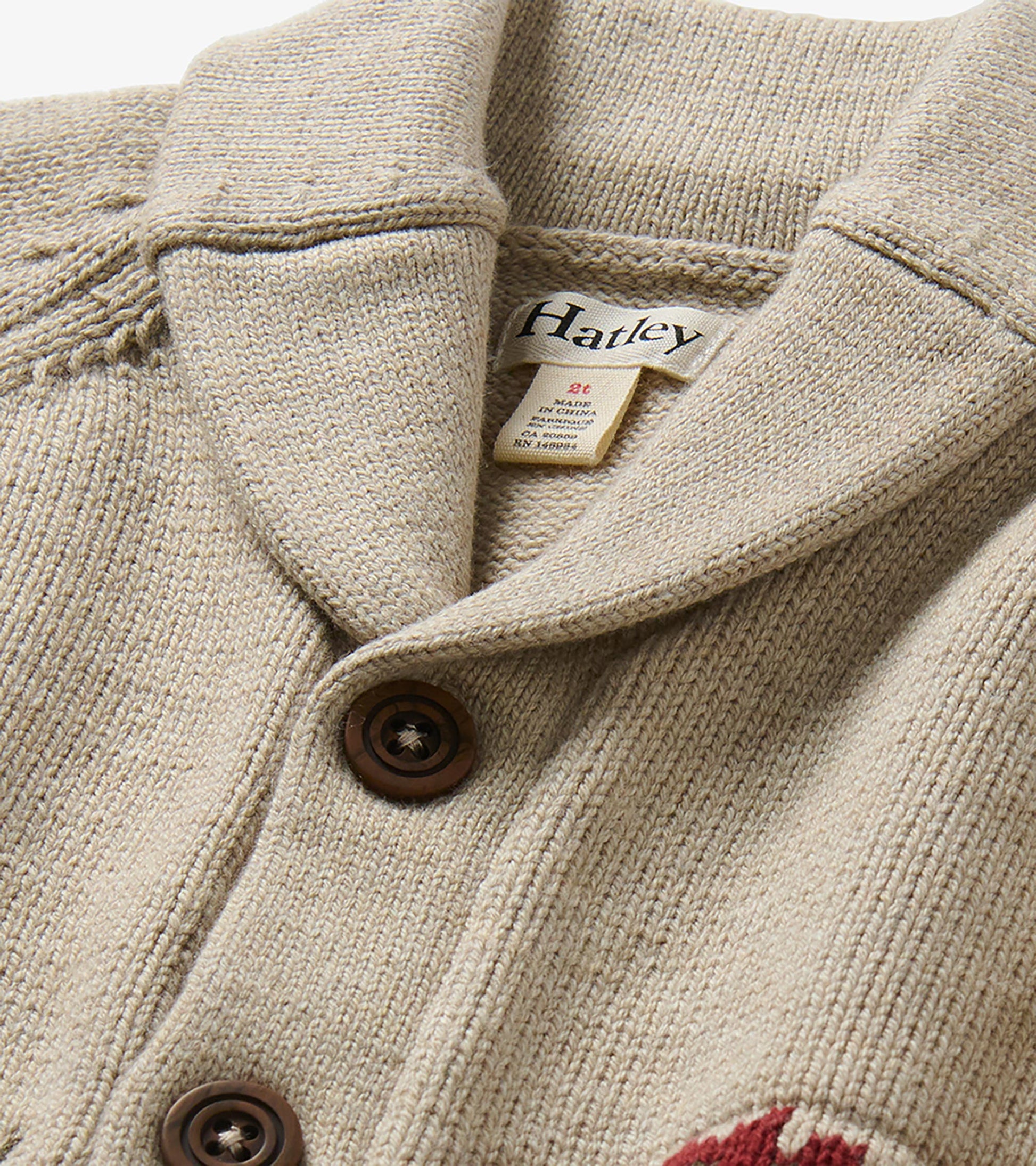 Close-up of oatmeal cardigan shawl collar, brown buttons, and Hatley neck label