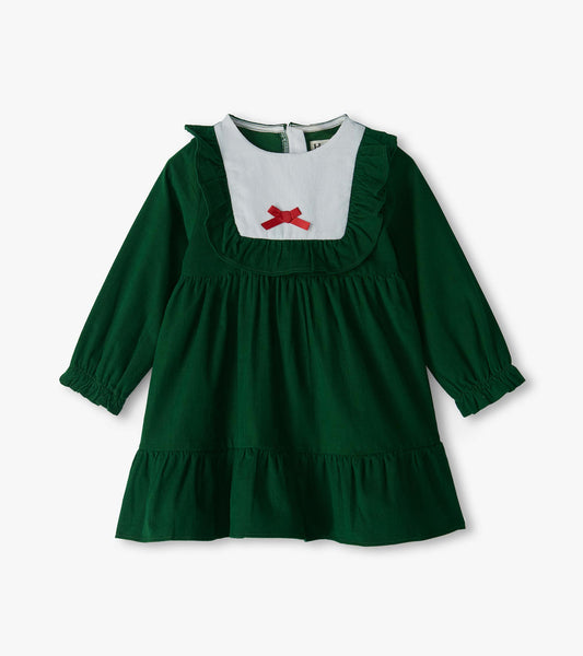 Front view of green long sleeve dress with white bib, ruffle trim, red bow, and tiered hem