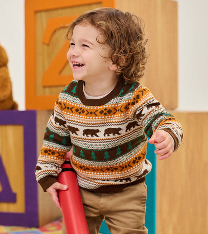 Toddler wearing a brown crew neck sweater with bear and tree fair isle pattern in green, amber, and cream