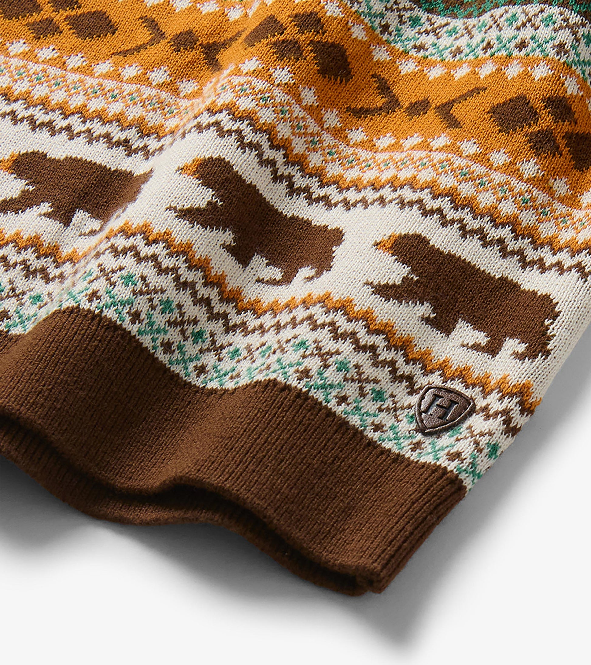 Close-up of sweater hem with brown bear motif, fair isle stripes, and small Hatley H patch