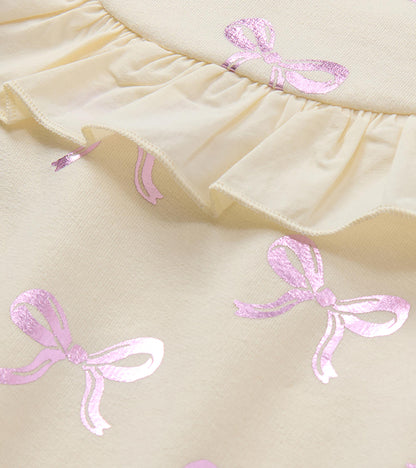 Close-up of cream dress ruffle trim with pink foil bow print