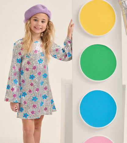 Girl wearing silver sequin dress with blue and pink flower dots and flared long sleeves