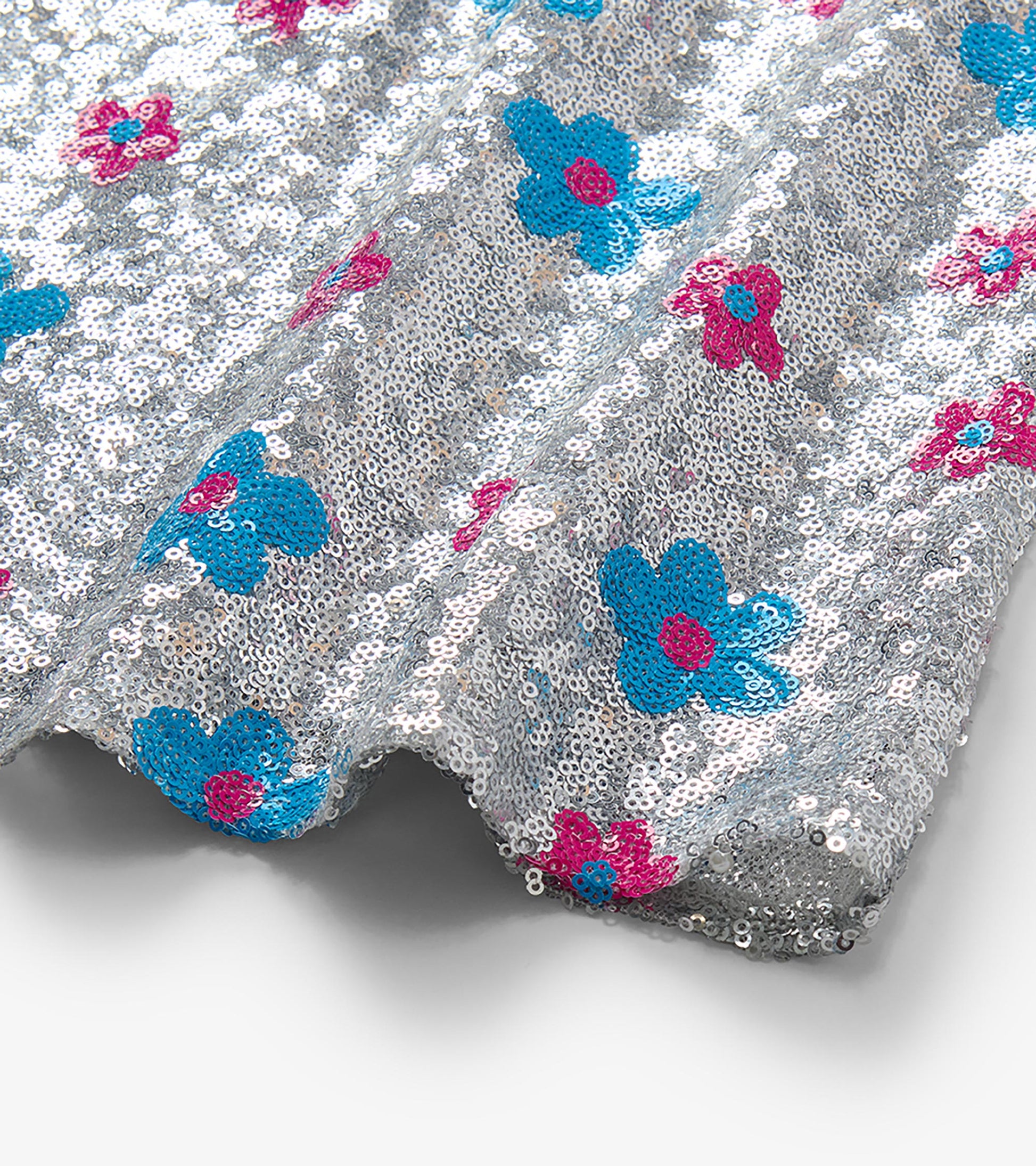 Close-up of silver sequins with blue and pink flower dot pattern on the dress