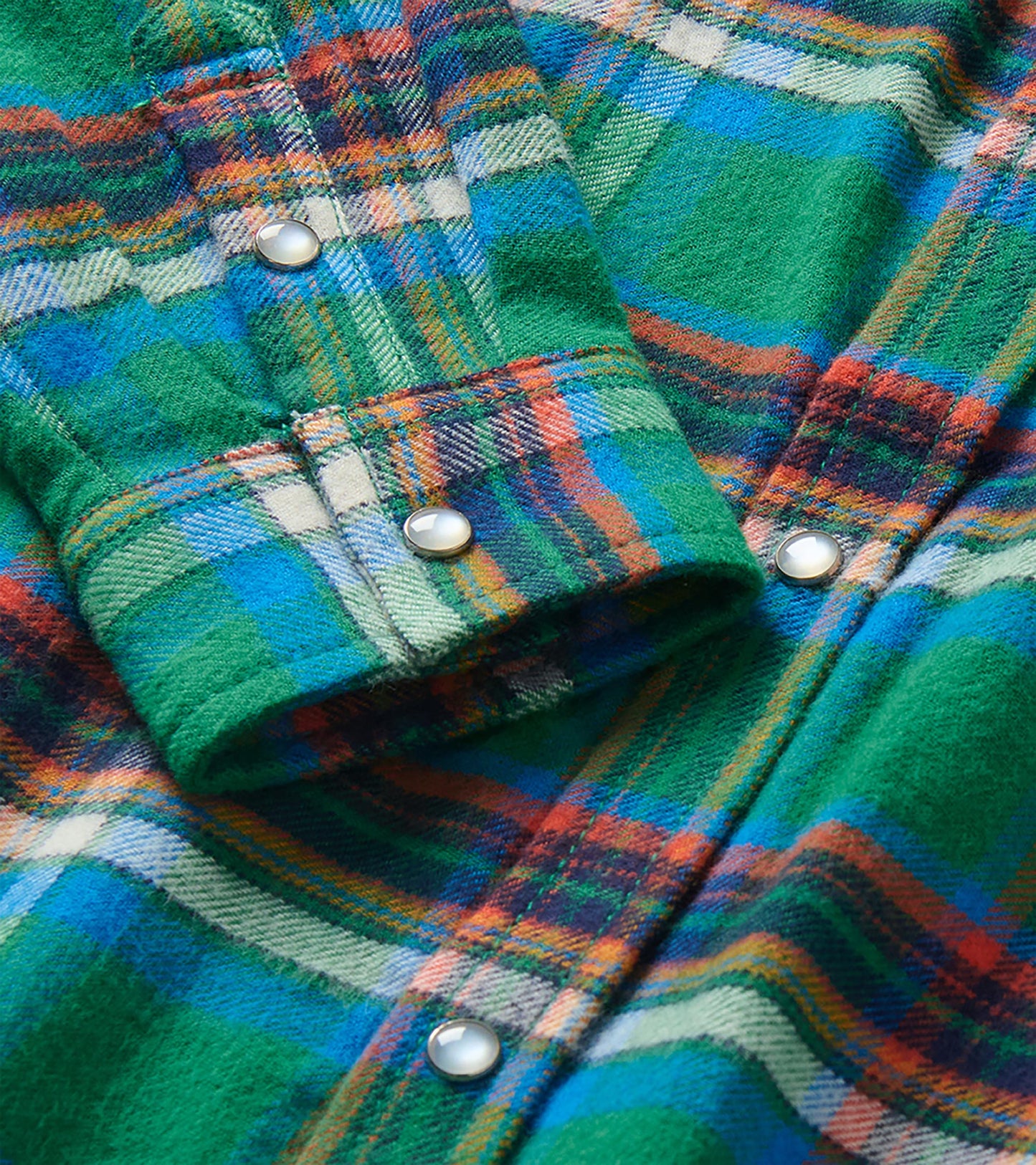 Close-up of green and blue plaid shirt showing snap buttons and cuff detail