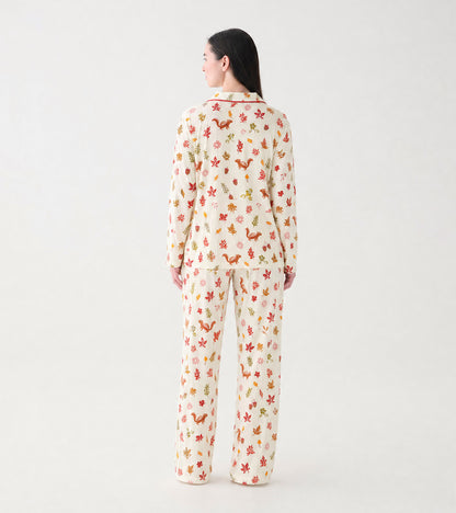 Women's cream pajama set with red piping and colorful fall print, shown from the back on a model