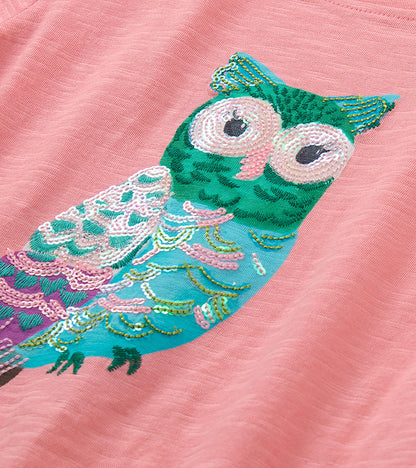 Close-up of multicolor owl graphic with pink sequined details on pink T-shirt
