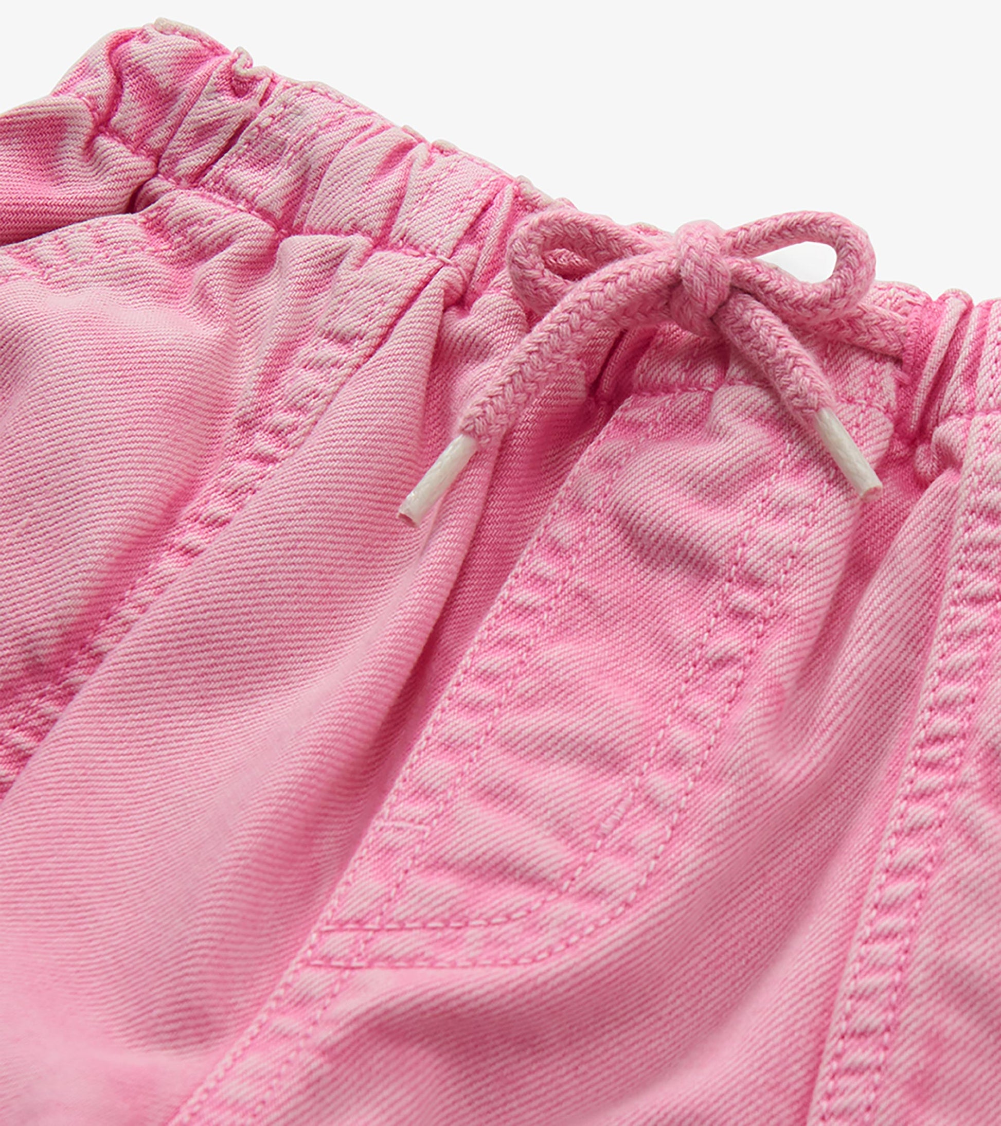 Close-up of flamingo pink jeans waistband with elastic waist, drawcord tie, and front pocket stitching