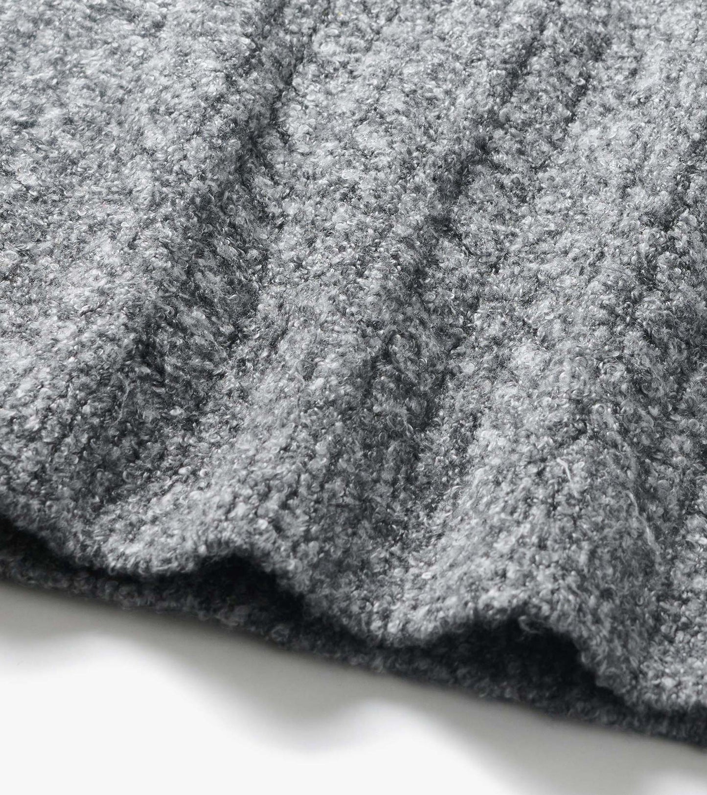 Close-up of grey boucle sweater fabric with a soft, curly texture