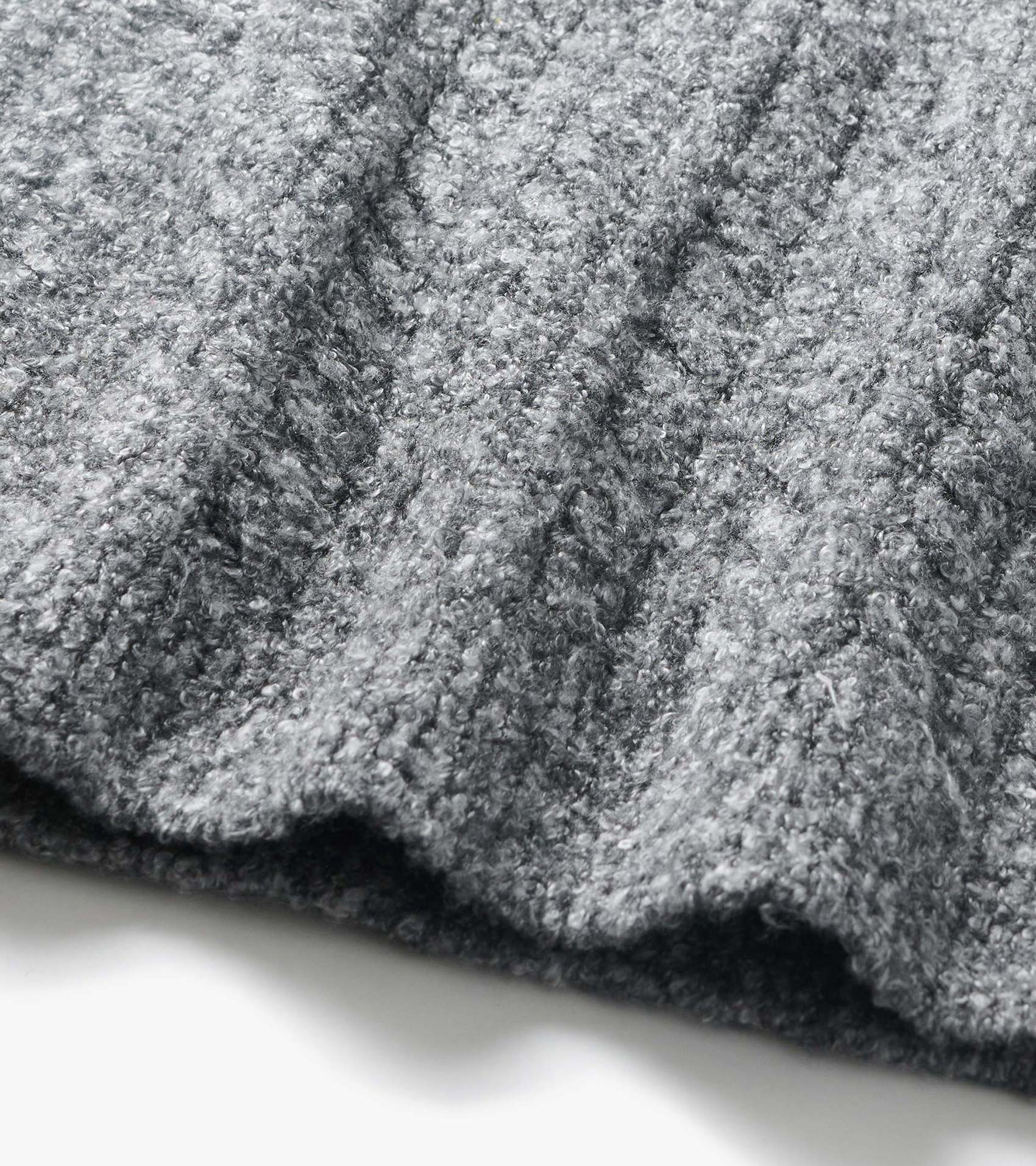 Close-up of grey boucle sweater fabric with a soft, curly texture