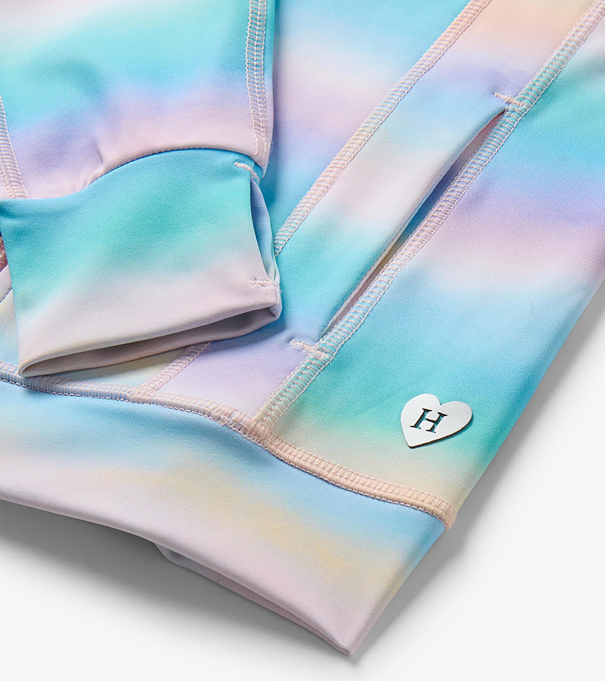 Close-up of pastel ombre jacket cuff and sleeve with thumbhole and white heart-shaped H logo