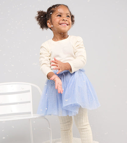 Toddler wearing a cream long-sleeve glitter-speckled top with puff shoulders