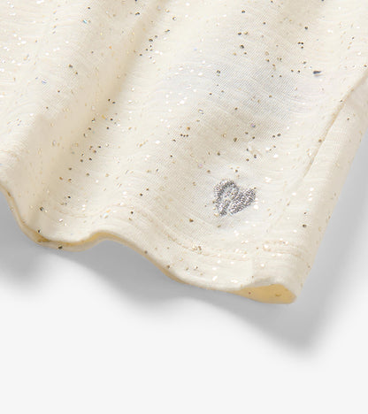 Close-up of cream glitter-speckled hem with a small silver heart detail