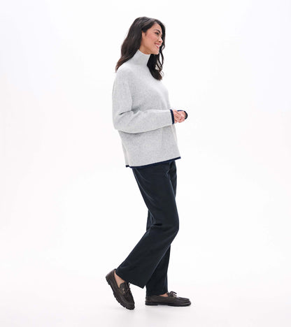 Side view of athletic grey mock neck sweater with relaxed fit and navy trim at cuffs and hem