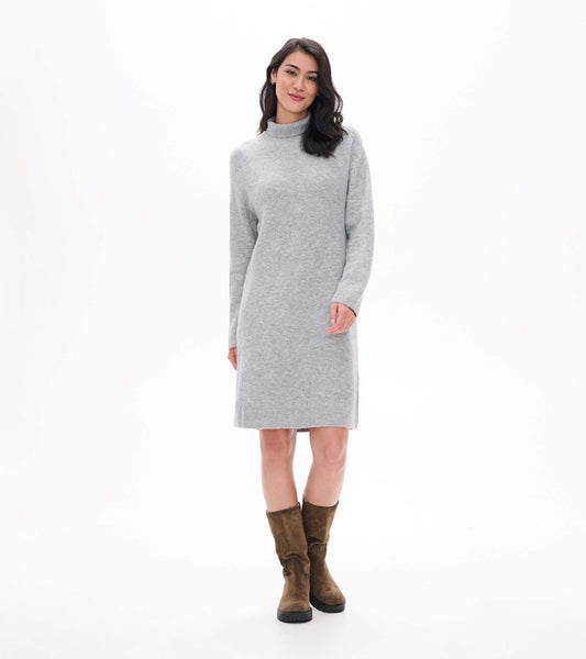 Model wearing grey melange turtleneck sweater dress with long sleeves and knee-length straight silhouette