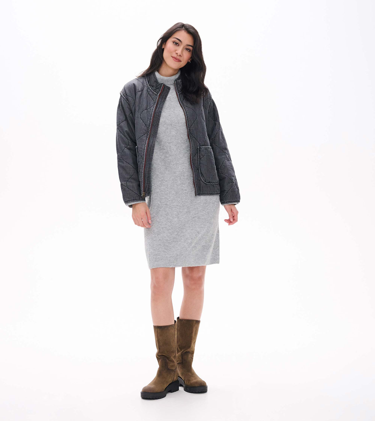 Grey melange turtleneck sweater dress layered under a dark quilted jacket on model