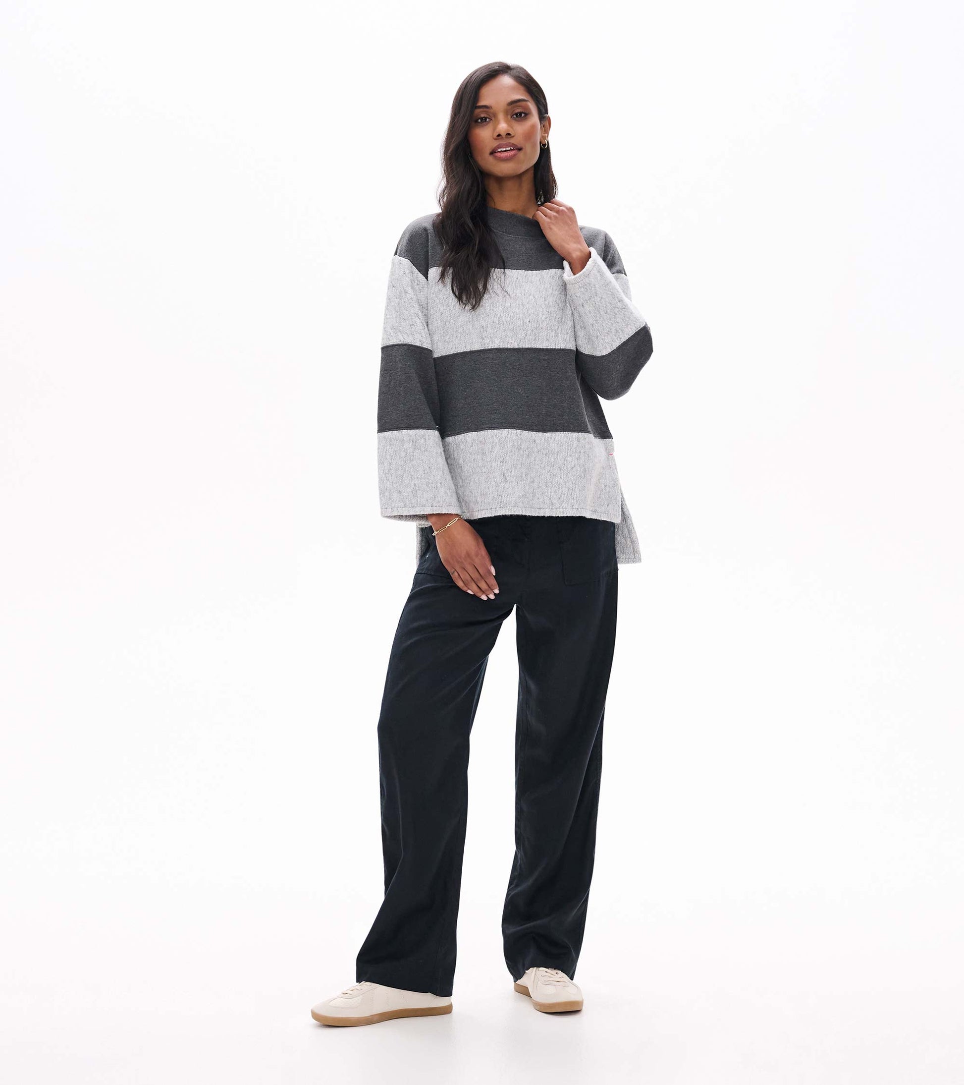 Full front view of charcoal and light gray striped long sleeve top with wide sleeves and high-low hem