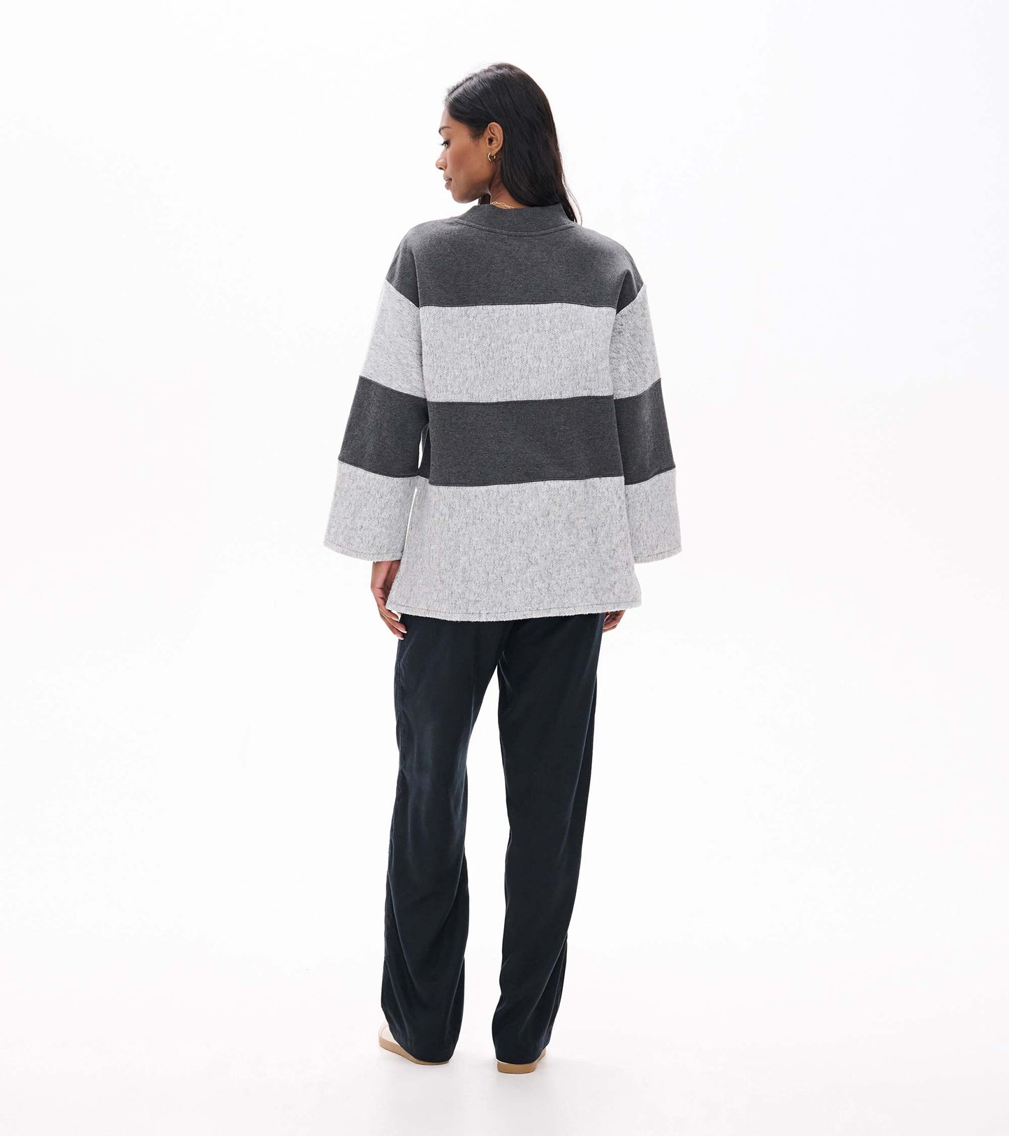 Back view of charcoal and light gray striped long sleeve top with wide sleeves and high-low hem