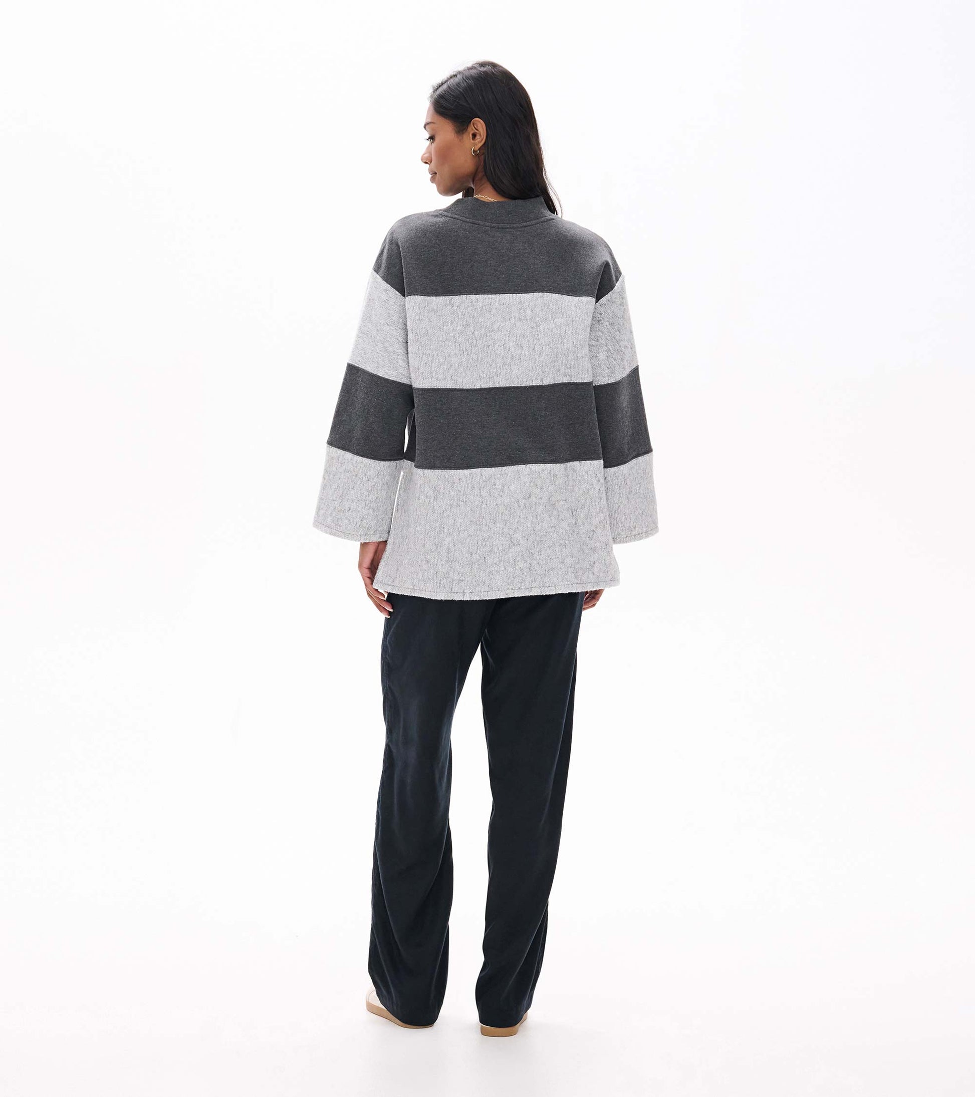 Back view of charcoal and light gray striped long sleeve top with wide sleeves and high-low hem