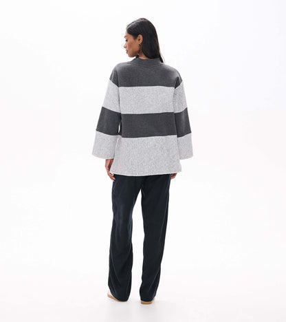Back view of charcoal and light gray striped long sleeve top with wide sleeves and high-low hem