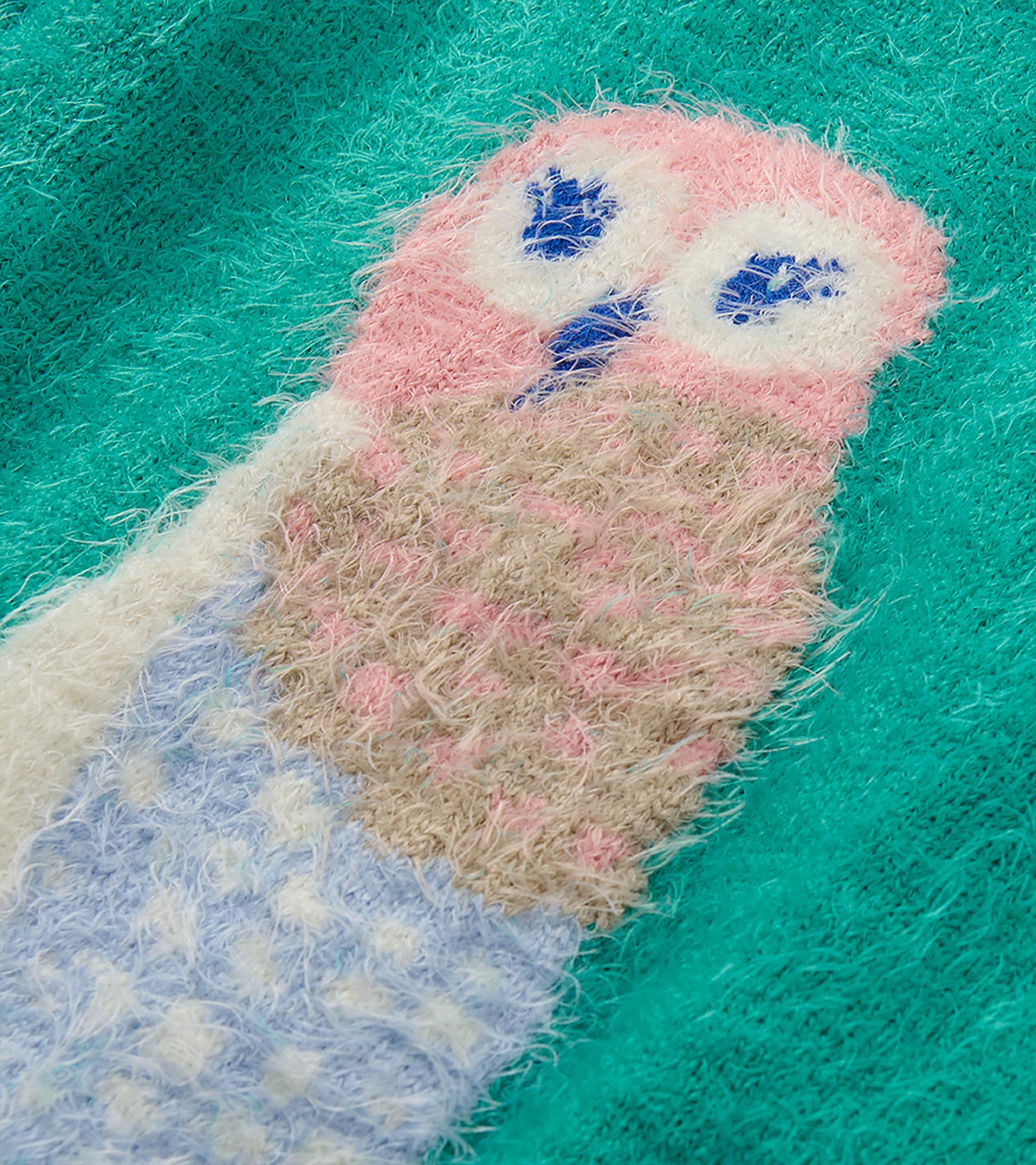Close-up of pastel owl graphic on teal fuzzy sweater