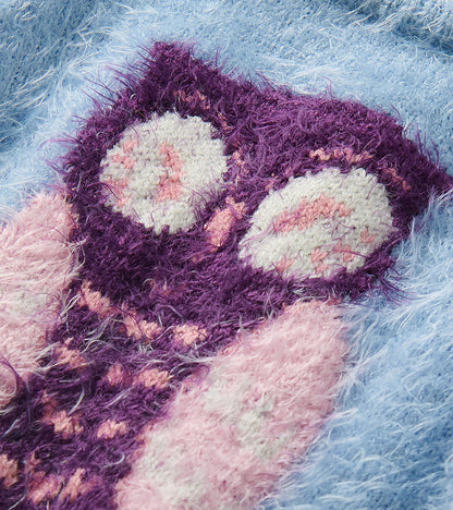 Close-up of the pink and purple owl knit detail on the sky blue furry sweater
