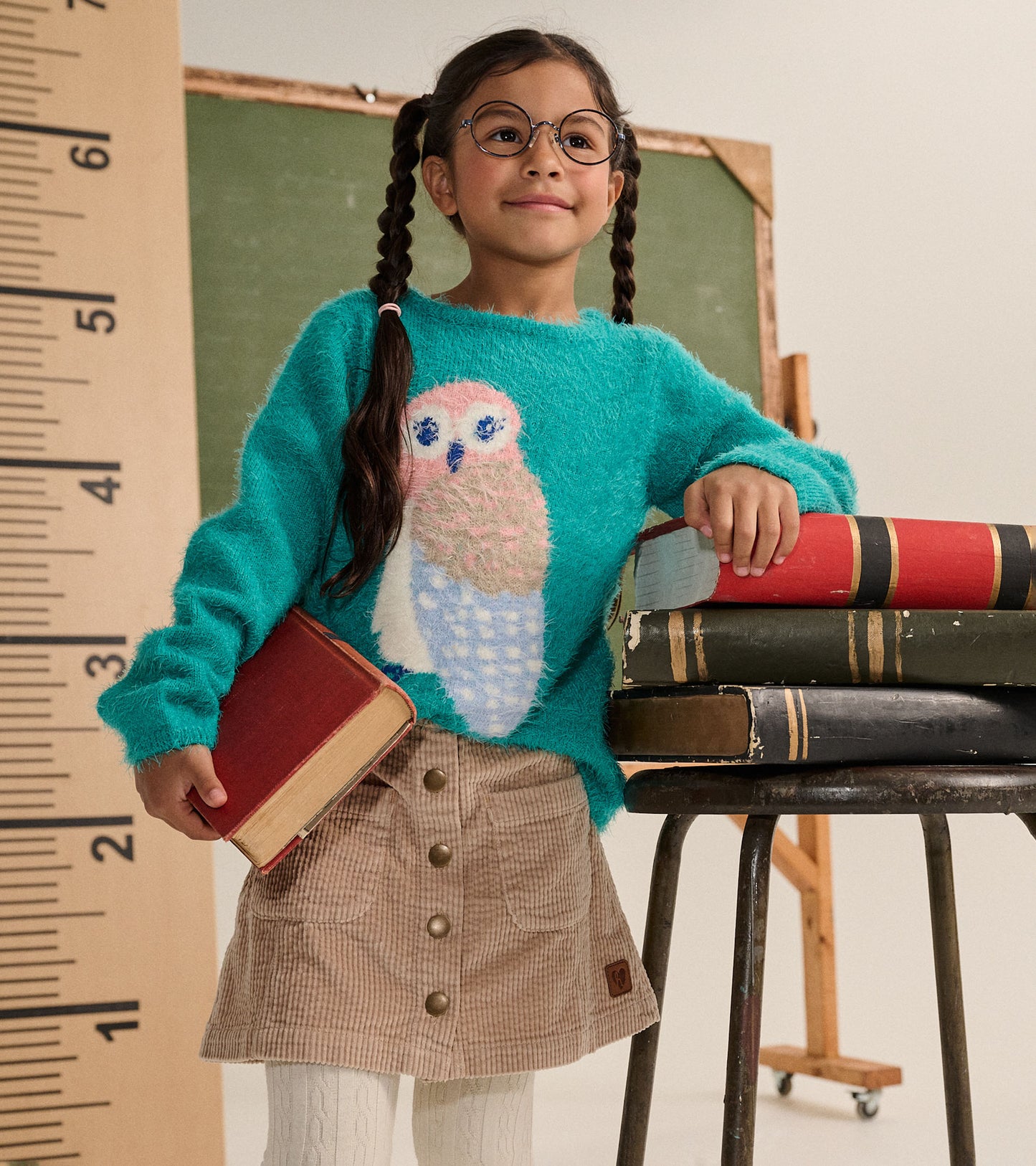 Girl wearing taupe corduroy A-line skirt with front snaps and patch pockets