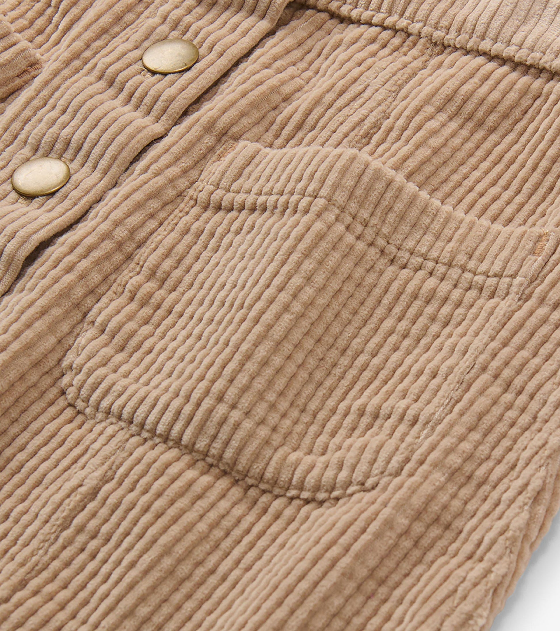 Close-up of taupe corduroy skirt showing front patch pocket and snap placket detail