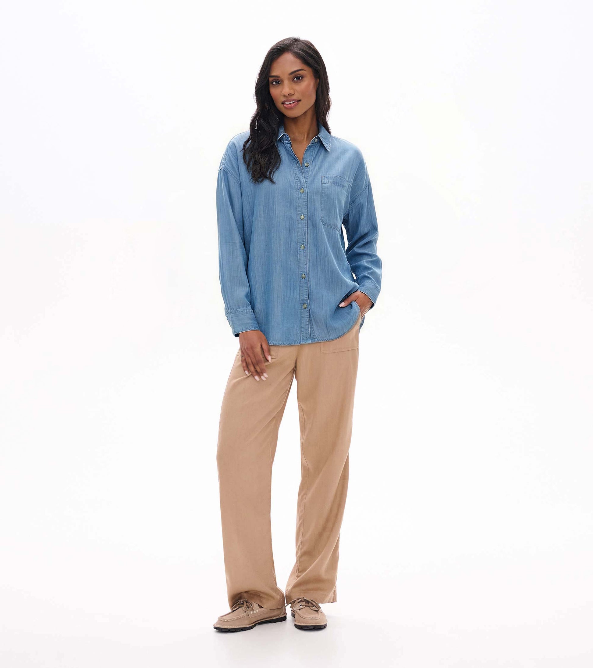 Front view of relaxed light blue wash button-down shirt on model with chest pocket and curved hem