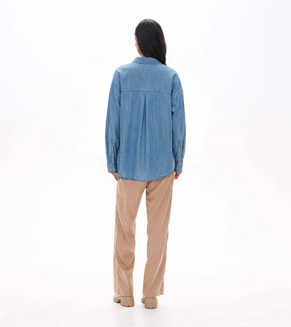 Back view of relaxed light blue wash button-down shirt on model with back pleat and curved hem