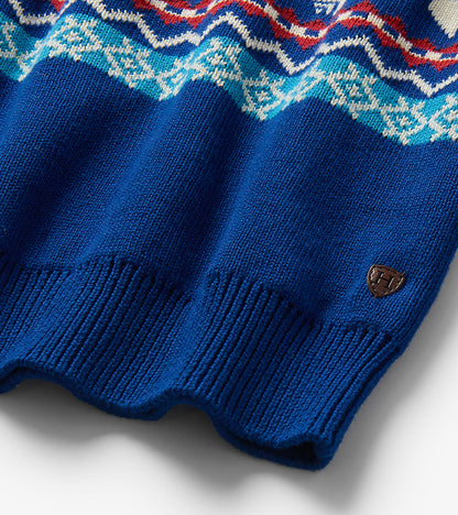 Close-up of blue sweater hem with ribbed trim, Fair Isle pattern, and small brown logo patch