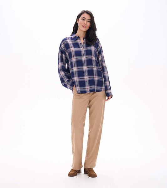 Front view of relaxed navy plaid button-down shirt with long sleeves and curved hem on model