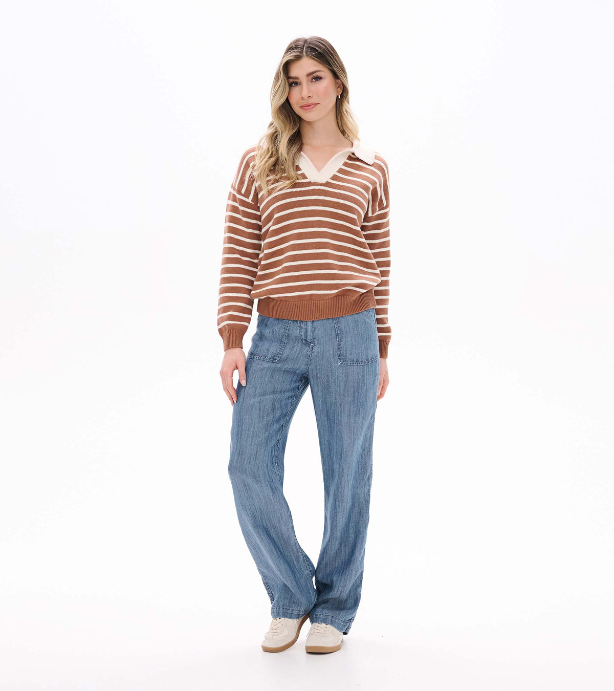 Full front view of camel and cream striped Johnny collar sweater worn with blue pants