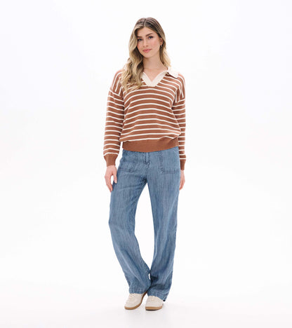 Full front view of camel and cream striped Johnny collar sweater worn with blue pants