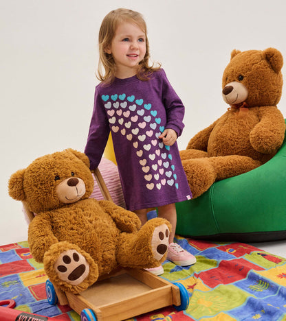 Toddler girl wearing a purple long sleeve dress with multicolor heart appliqués on the front
