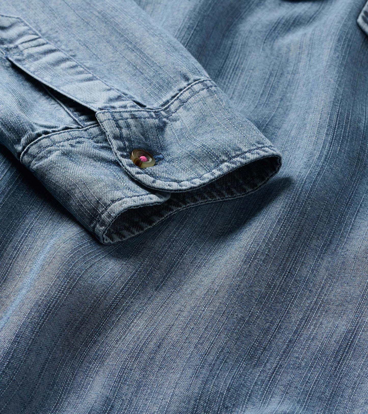 Close-up of blue acid rinse dress cuff with button tab and visible seam detail