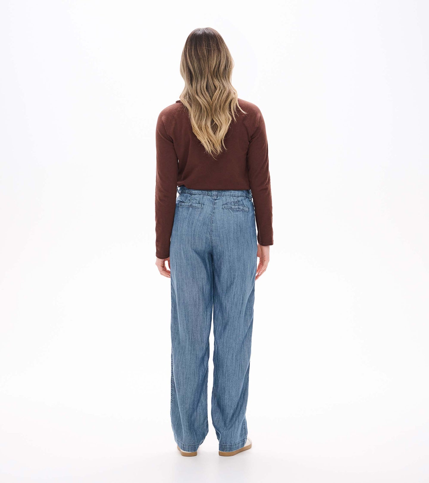 Back view of blue acid rinse wide leg pants on model with high waist and back welt pockets