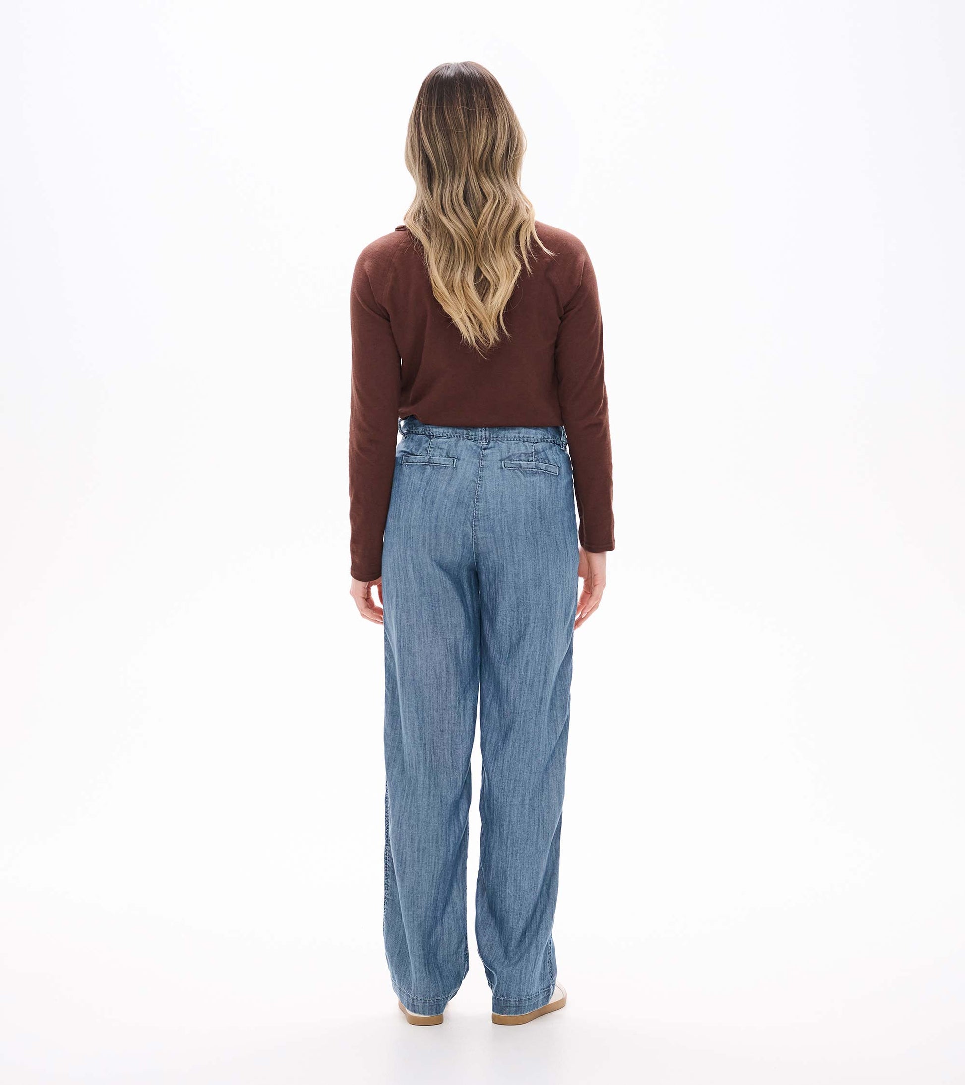 Back view of blue acid rinse wide leg pants on model with high waist and back welt pockets