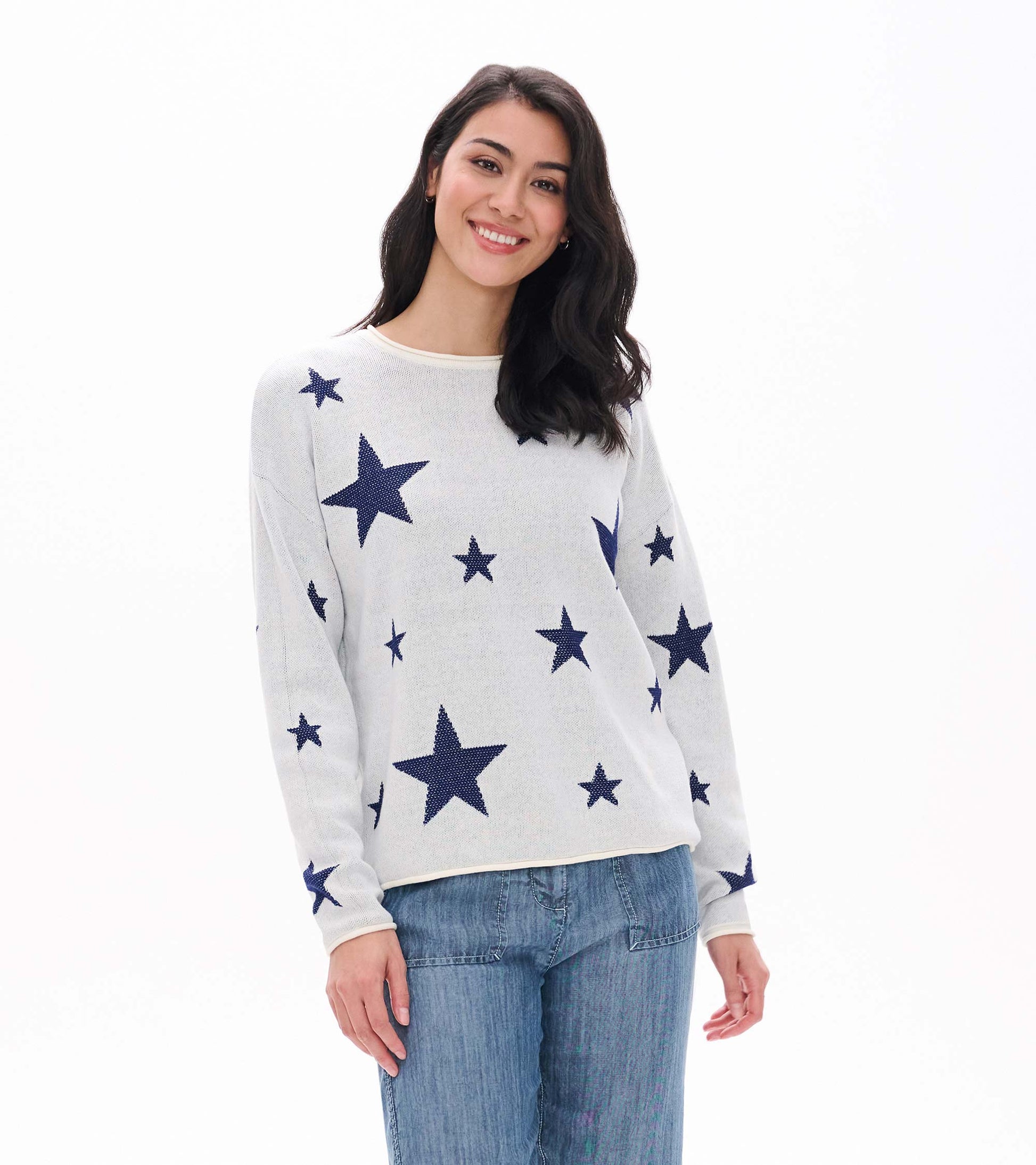 Front view of cream sweater with navy star pattern and rolled edges, worn with blue pants