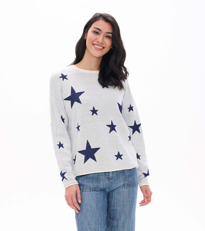 Front view of cream sweater with navy star pattern and rolled edges, worn with blue pants
