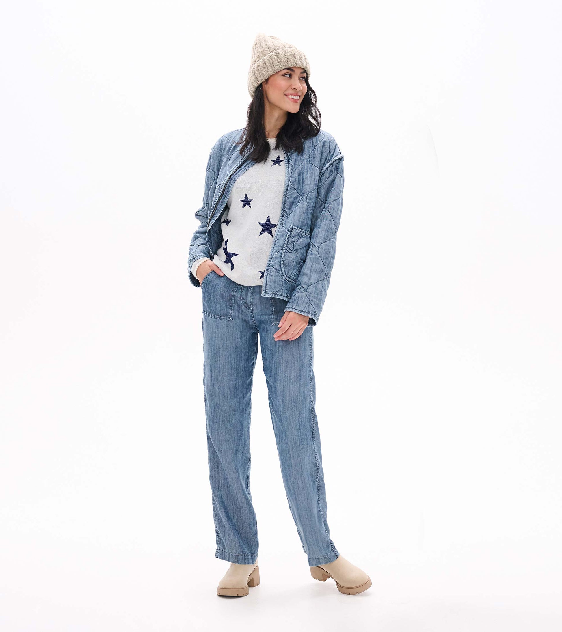 Cream sweater with navy stars layered under a blue quilted jacket and knit beanie