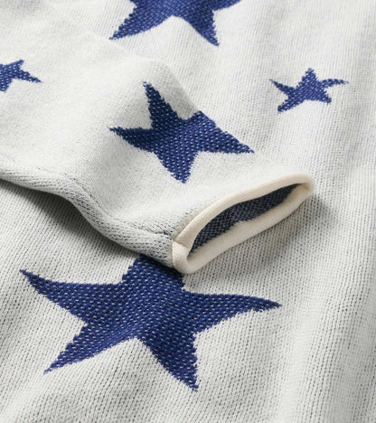 Close-up of cream sweater sleeve with rolled cuff and navy star pattern