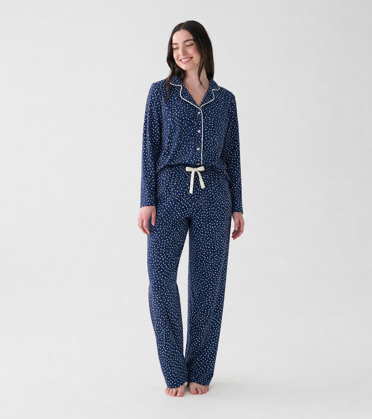 Model wearing navy polka dot pajama set with white piping and drawstring pants, front view