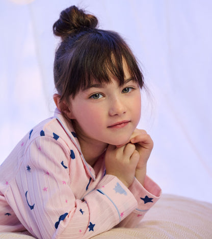 Close-up of girl wearing pink moon, star, and cloud print pajamas with blue piping